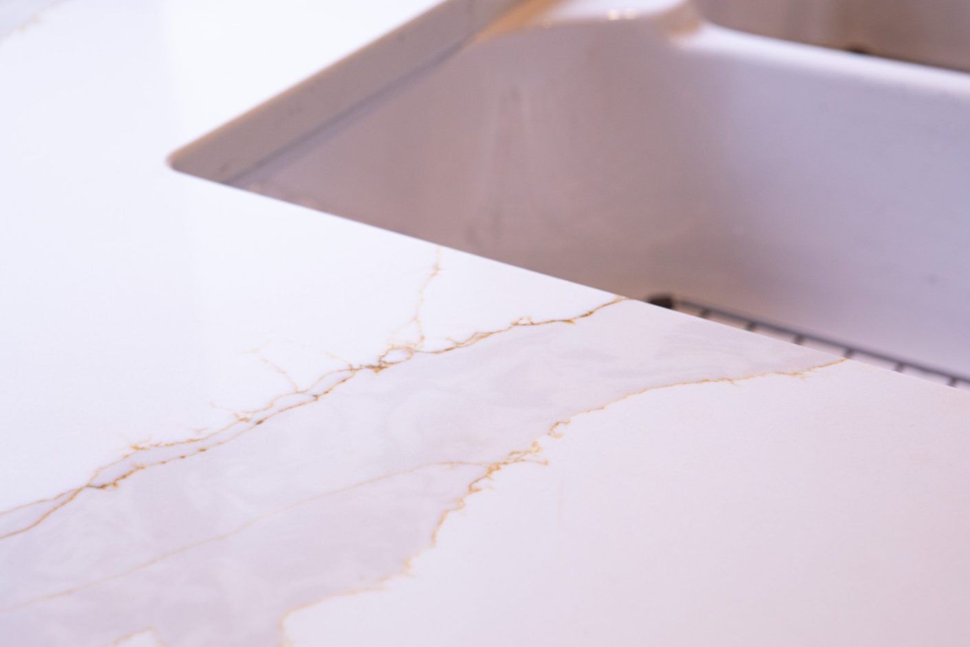 Britannicca Calacatta Quartz close-up showing warm grey veining with soft branching movement across a white surface