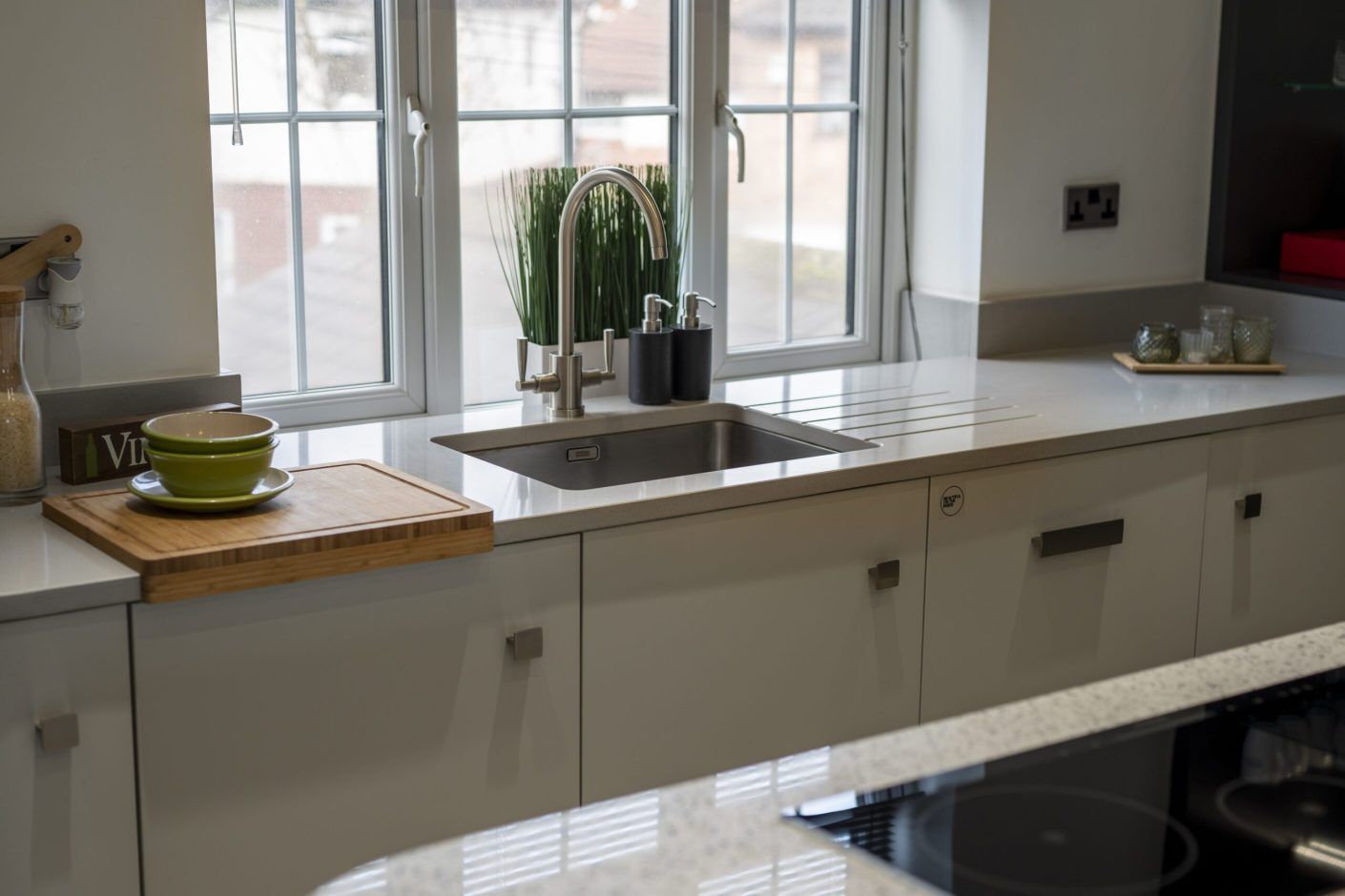 Carnie Quartz worktop run beneath a window with sink cut-out and light speckled finish across the surface