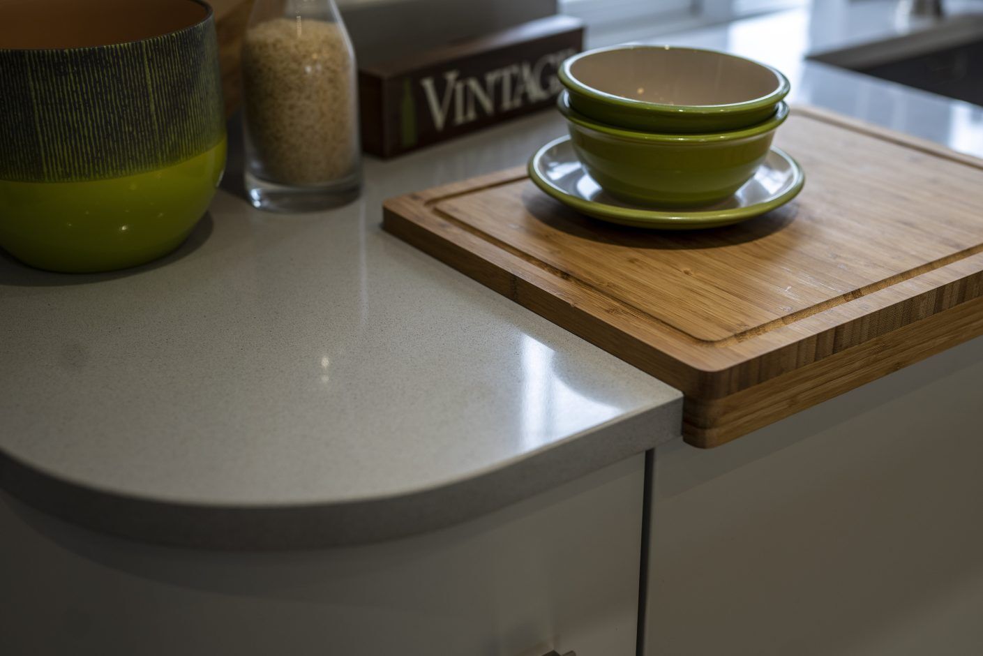 Carnie Quartz worktop corner close-up showing rounded end profile and light speckled finish beside a wooden board