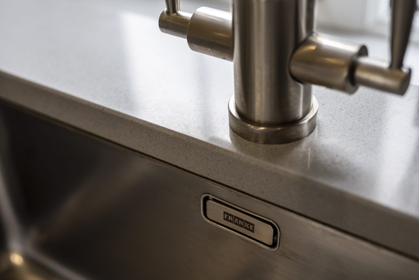 Carnie Quartz worktop by the sink showing clean cut-out lines and a brushed metal tap base on the surface