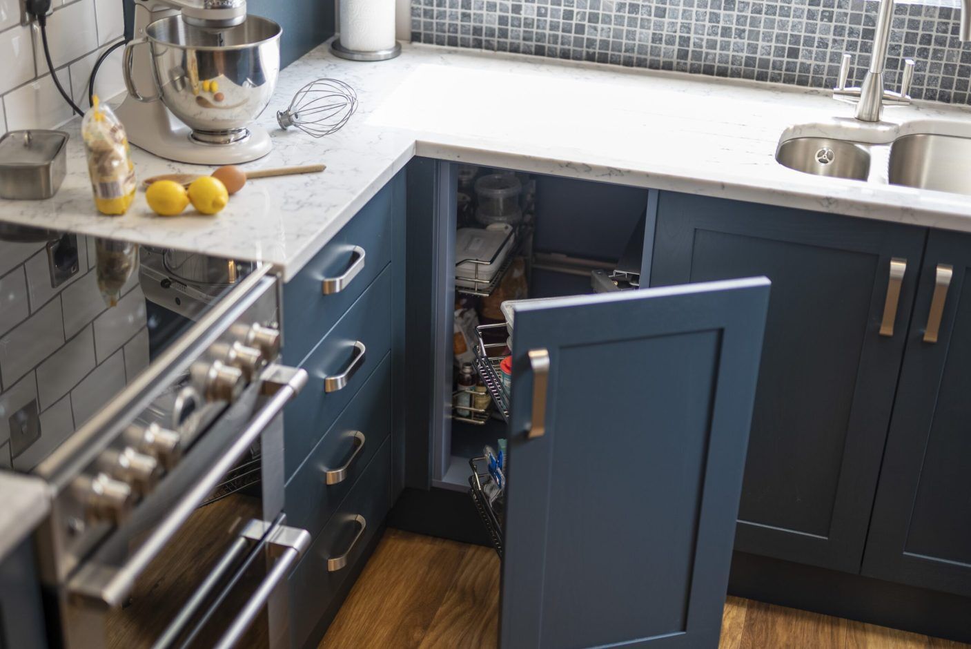 Arabescato Quartz worktop in a corner kitchen run with dark blue cabinetry and grey veining across the surface