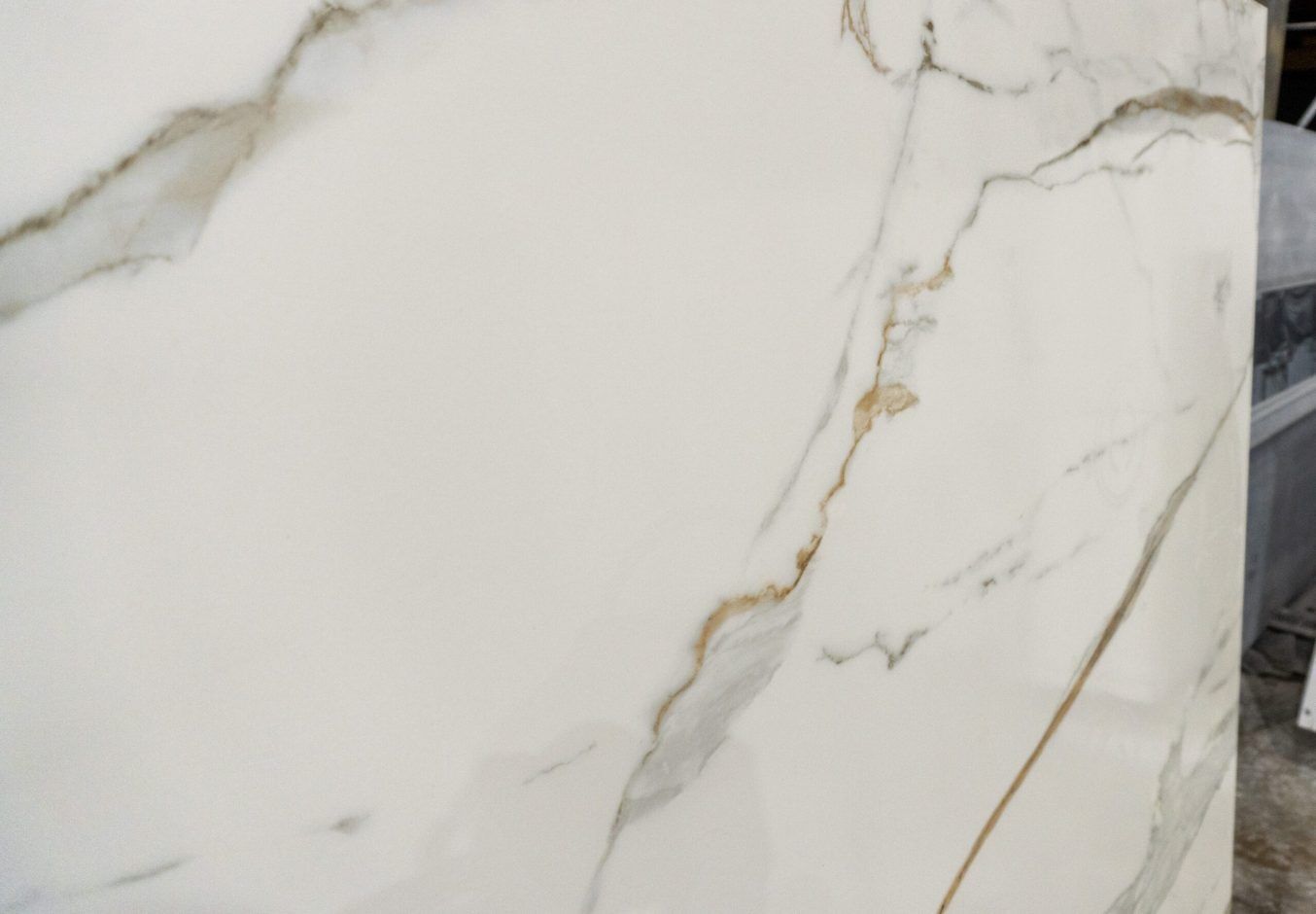 Calacatta Vagli Gold Porcelain close-up with a prominent gold vein and fine hairline veining on white