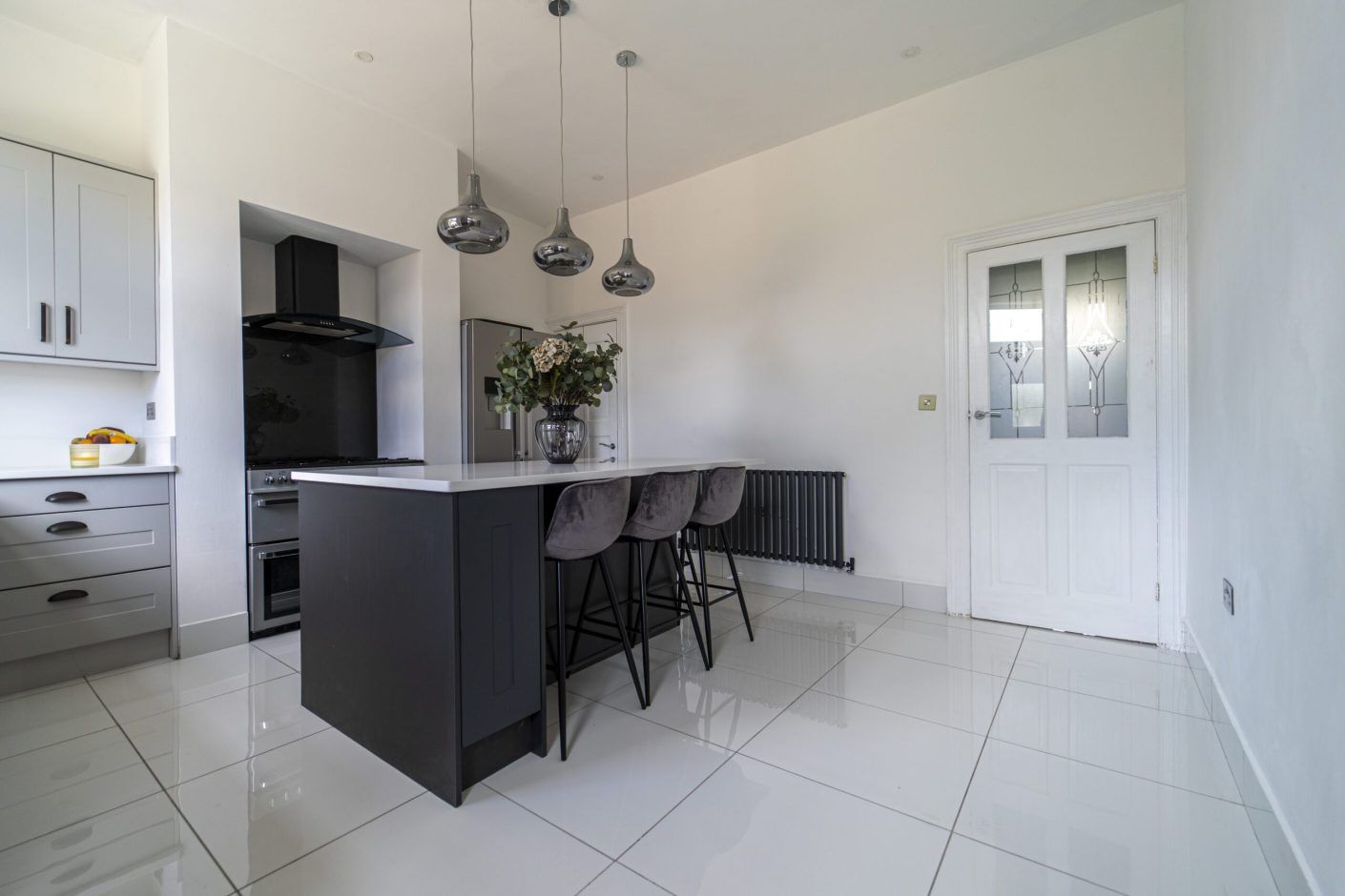 Open-plan kitchen with a Classic White Quartz island worktop and seating, showing a smooth bright surface