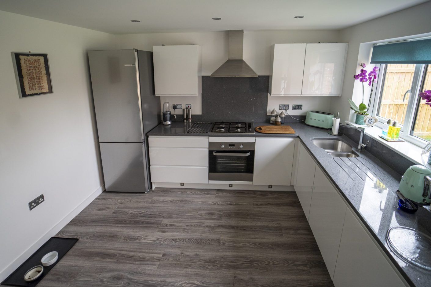Modern kitchen with grey speckled Quartz worktops fitted to an L-shaped run and hob area