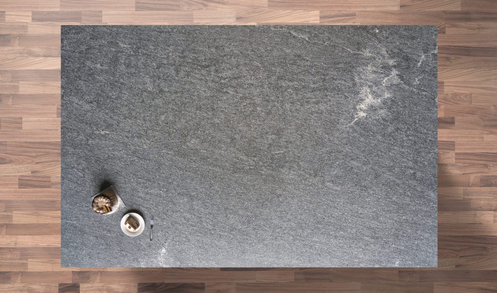 Overhead view of Diamond Galaxy leather Granite worktop showing a dark grey textured surface with subtle natural movement, photographed from above with styling near the edge.