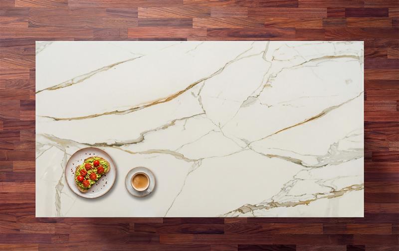 Calacatta Vagli Gold Porcelain worktop surface with warm gold veining across a white slab, styled with a small dish and coffee cup