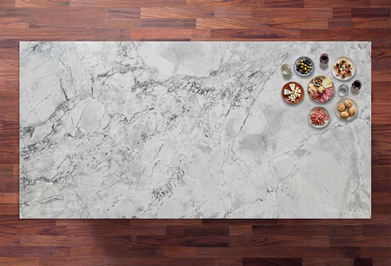 Calacatta Super White Porcelain slab with a bright white base and layered grey veining, photographed on a wood background with small props