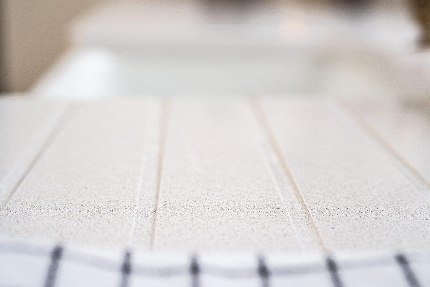 Low-angle close-up of Ice White Quartz drainer grooves showing the clean channel lines across the surface