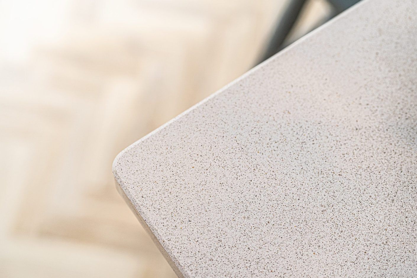 Close-up of Ice White Quartz worktop corner showing a rounded edge and fine speckled surface finish
