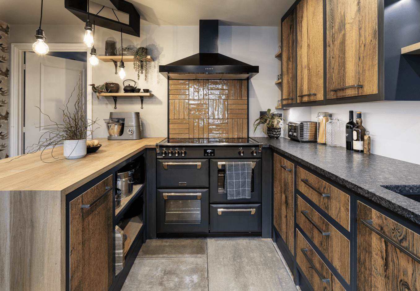 Wide kitchen view with Steel Grey leather Granite worktops on both sides, showing the textured Granite finish, rustic wood cabinetry and a black range cooker.