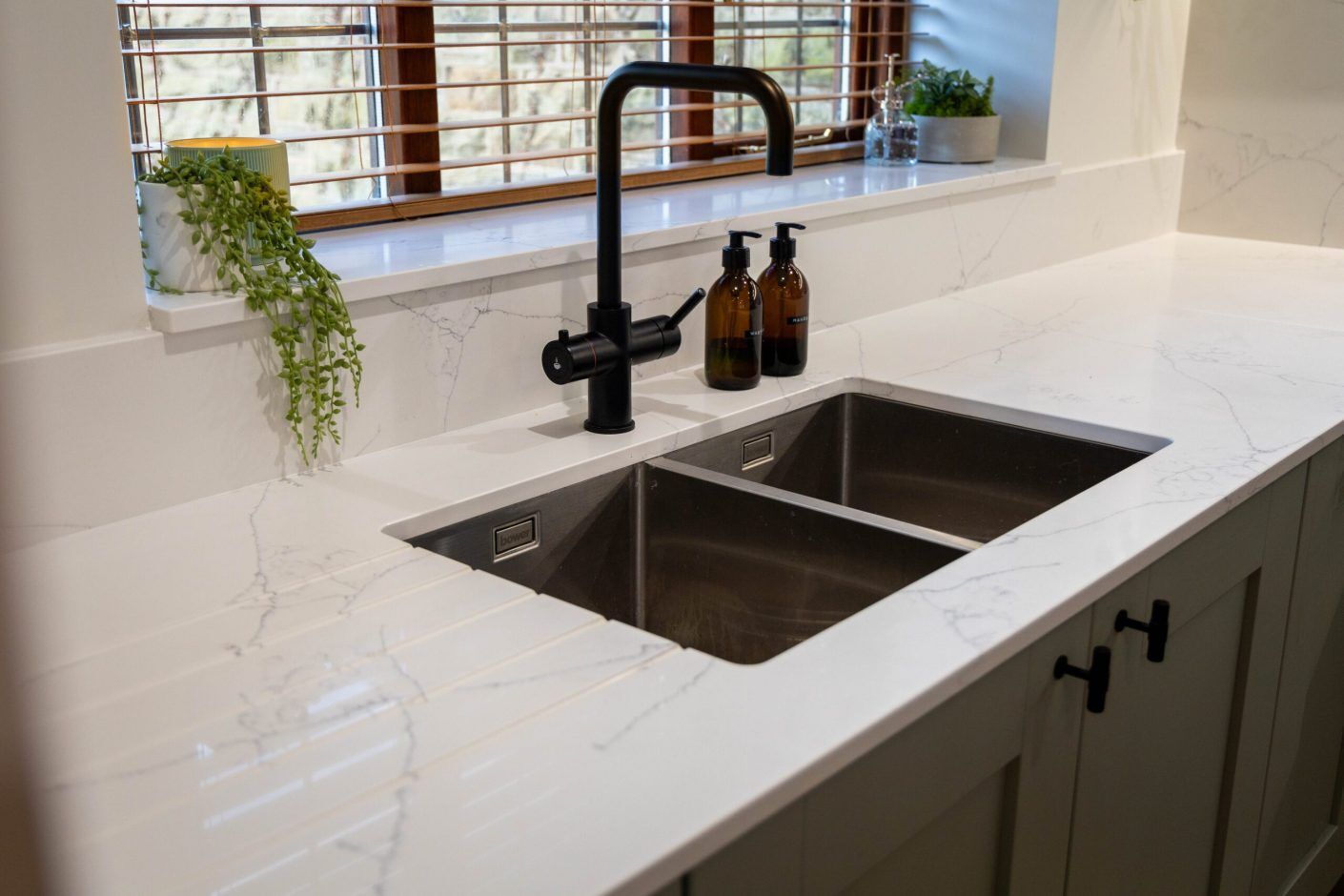 White Macaubus Quartz worktop with an undermount sink and black tap, showing subtle grey veining