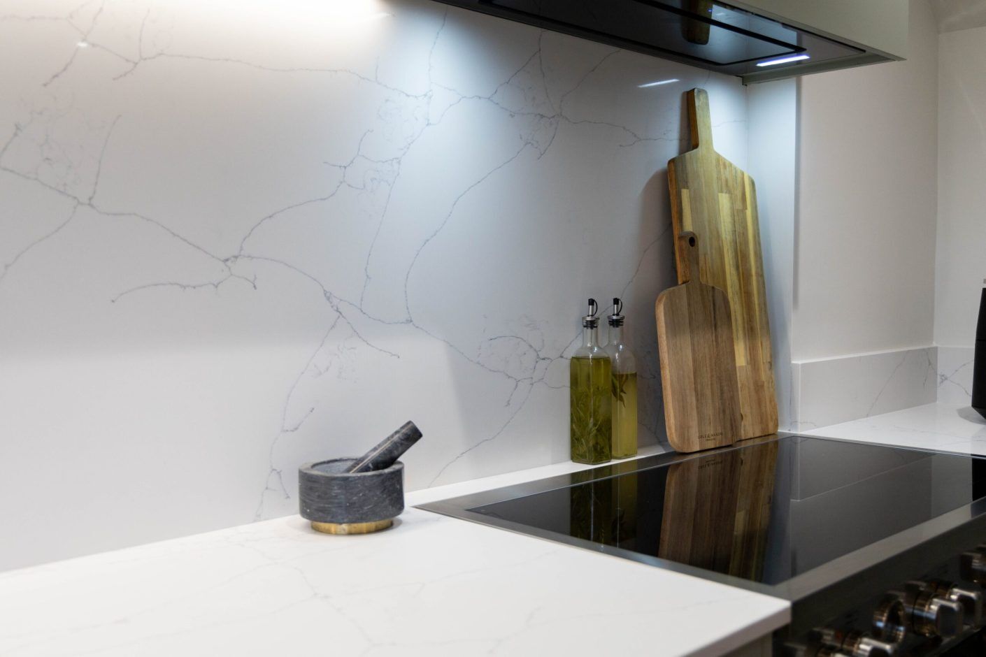 White Macaubus Quartz worktop and splashback corner with subtle veining beside kitchen accessories