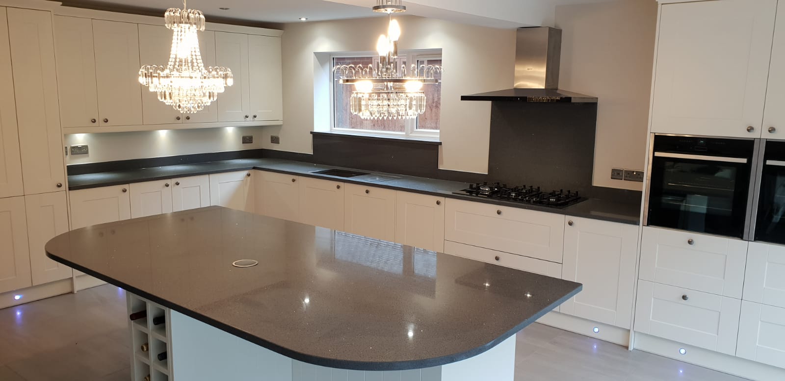 Grey Starlight Quartz island worktop with curved edge and matching perimeter worktops in a bright kitchen