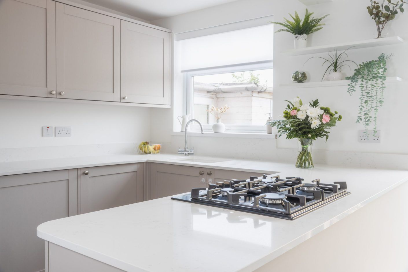 Bright kitchen view featuring Bluetta Carrara Quartz worktops with a hob set into the smooth white surface