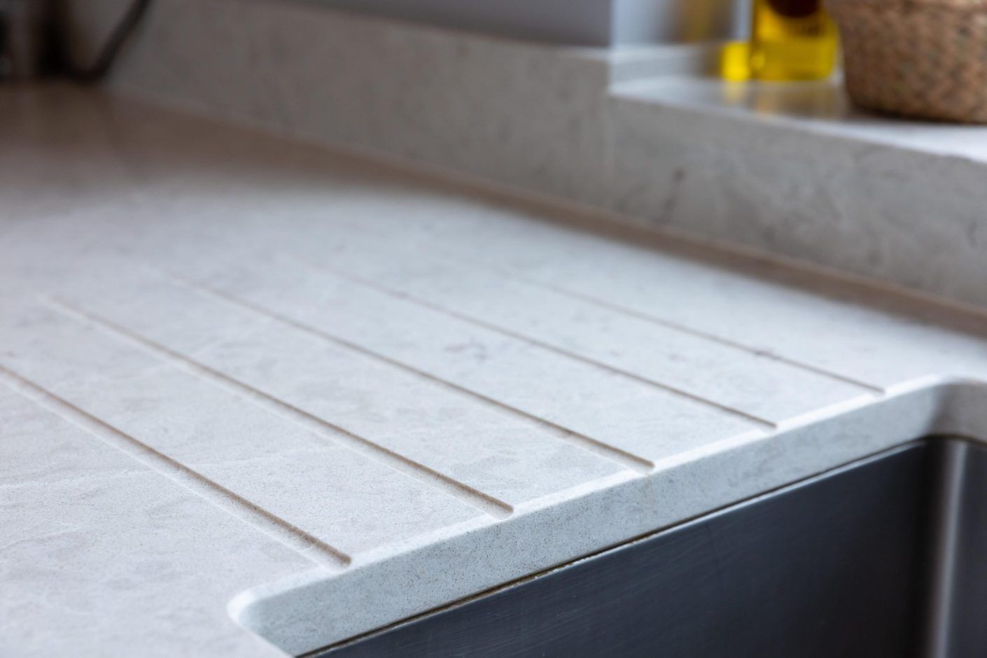 Grey Drift Quartz drainer grooves close-up showing crisp channels and soft stone-effect movement beside the sink