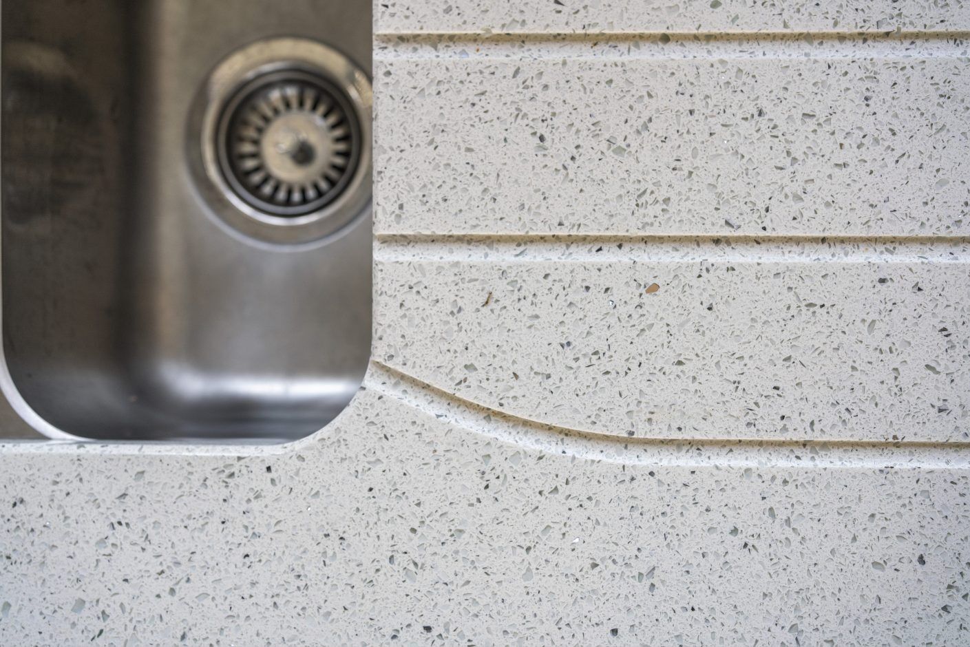 White Starlight Quartz worktop with drainer grooves beside a stainless steel sink