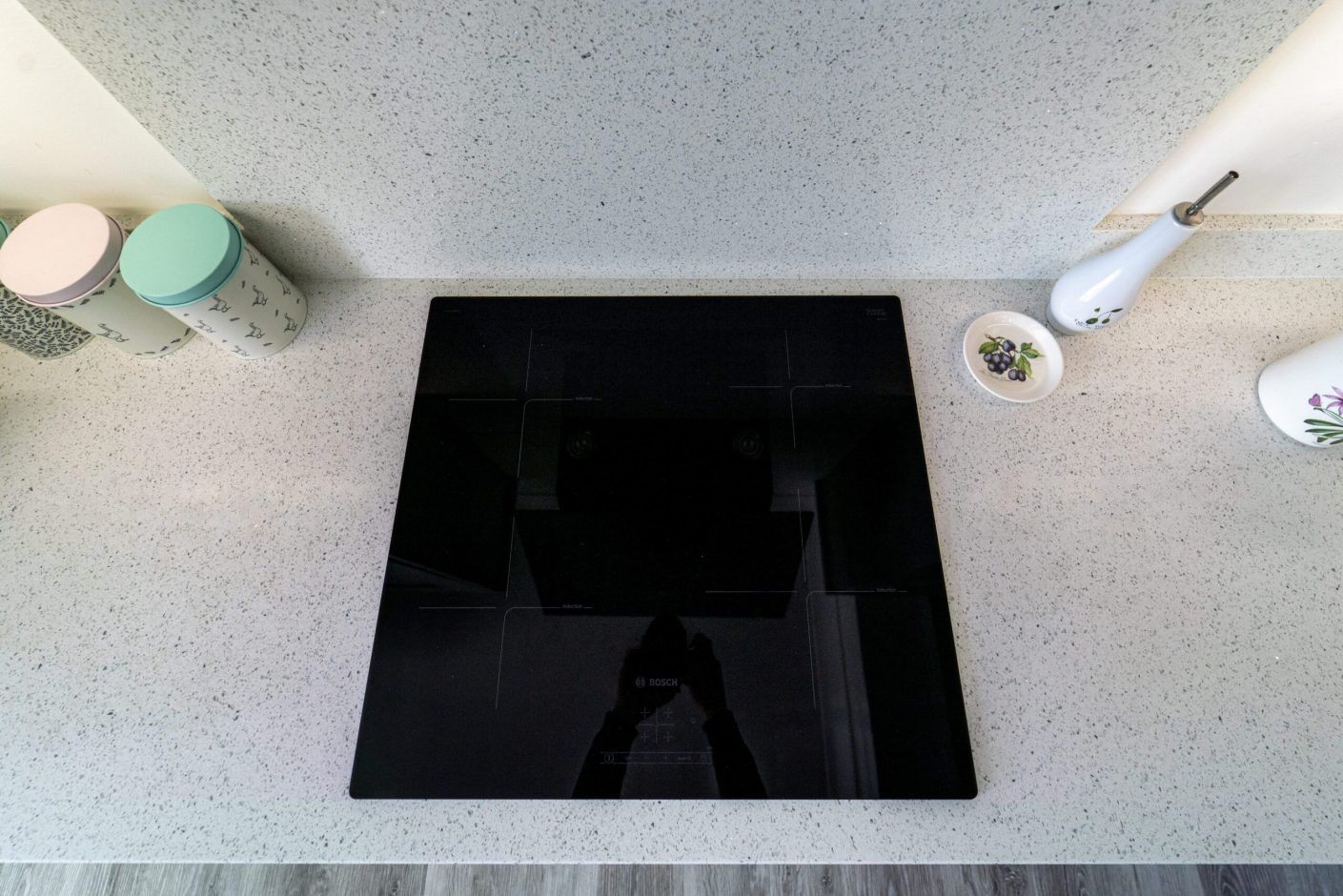 White Starlight Quartz worktops with black induction hob set into the surface in a modern kitchen