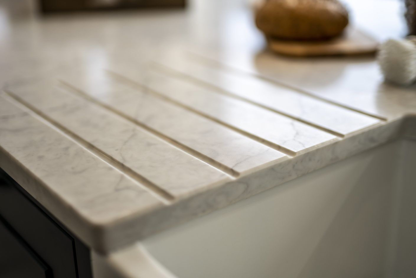 Super White Quartz worktop close-up showing integrated drainer grooves and clean edge detail on a light stone-effect surface