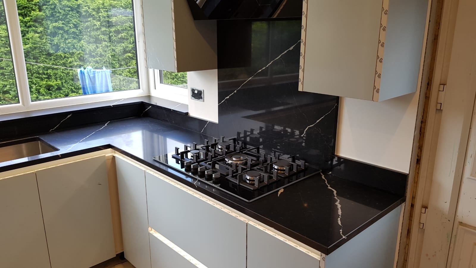 Nero Marquina Quartz worktop and splashback behind a gas hob showing bold white veining on a polished black surface