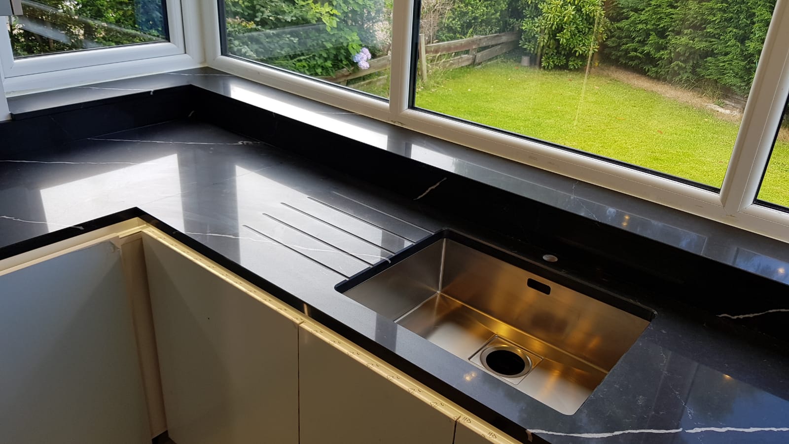 Nero Marquina Quartz worktop with inset stainless steel sink and draining area on a polished black veined surface