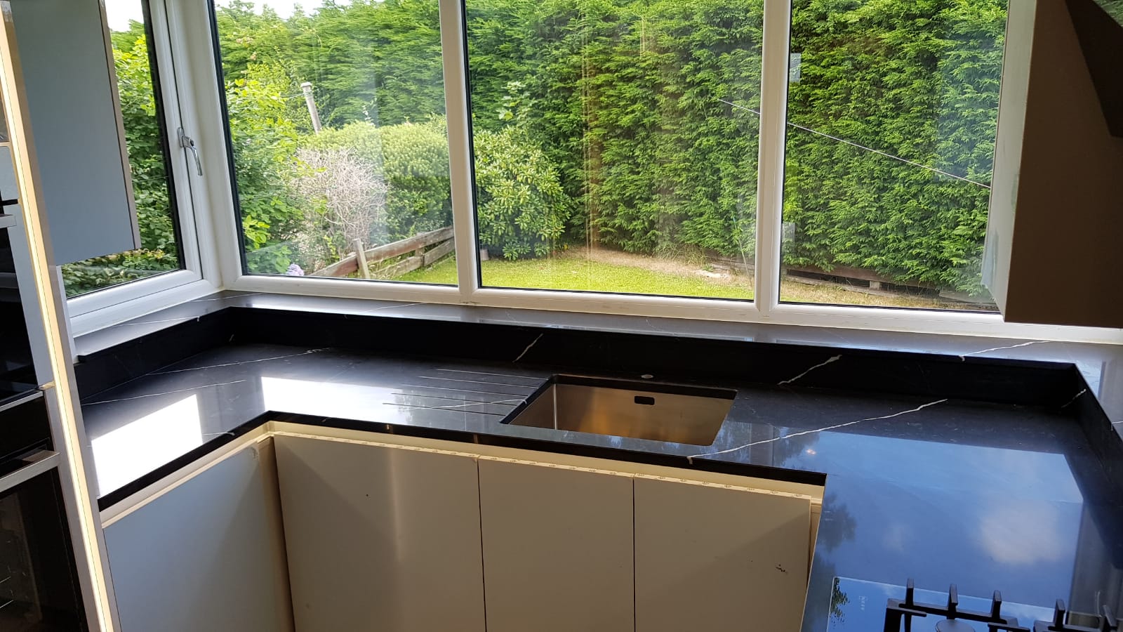 Nero Marquina Quartz worktop run beneath a window with inset sink cut-out and black surface with white veining