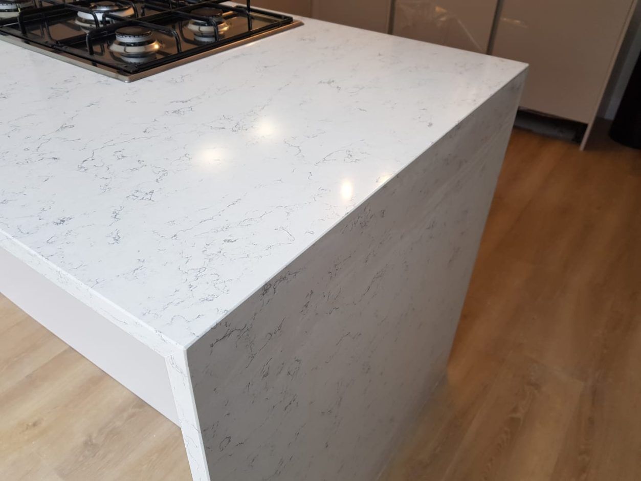 White Arabesque Quartz island edge close-up showing waterfall end detail and fine grey veining through the surface
