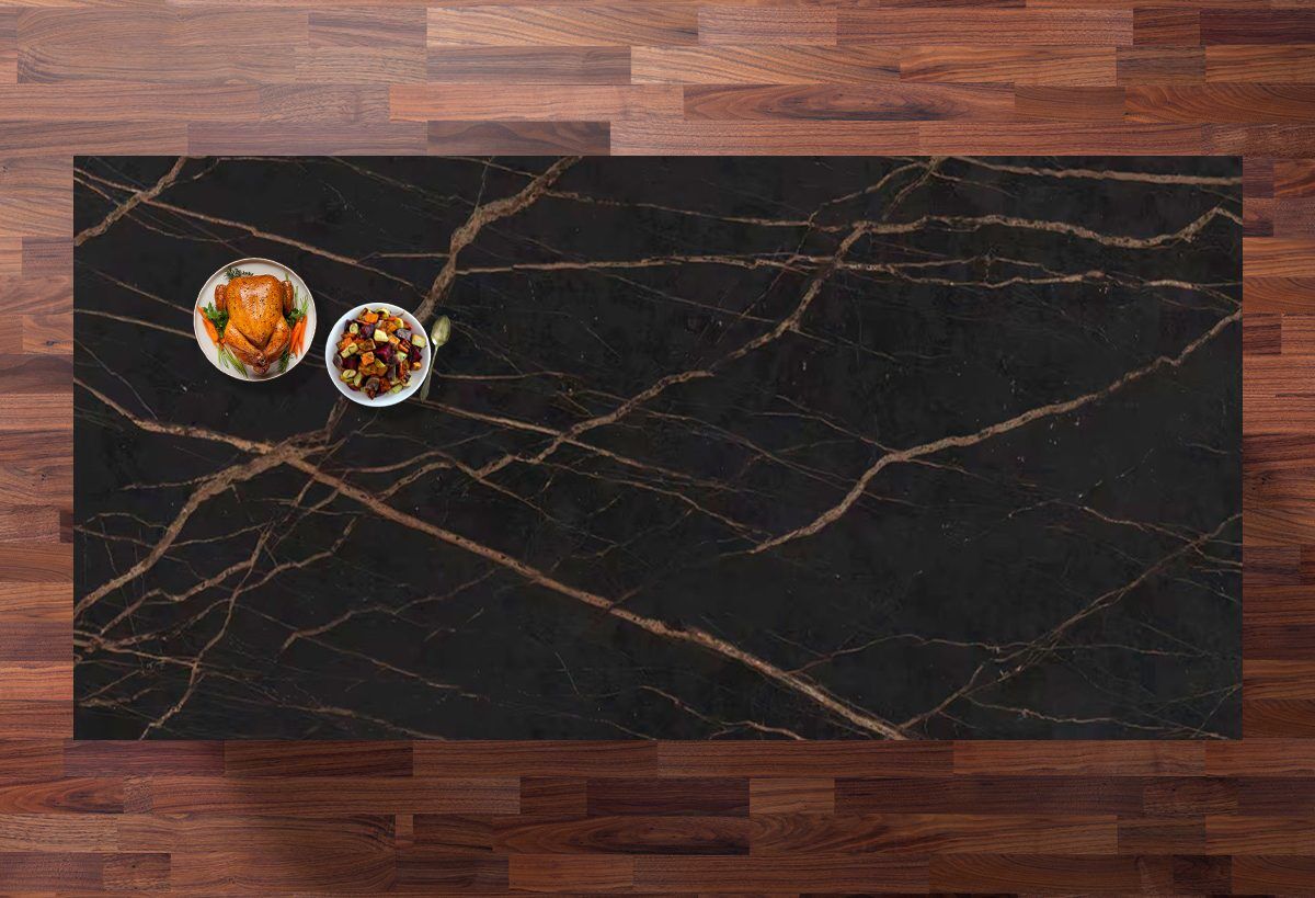 Top-down view of a Laurent Porcelain surface with gold veining on a dark background, styled with small dishes in the corner.
