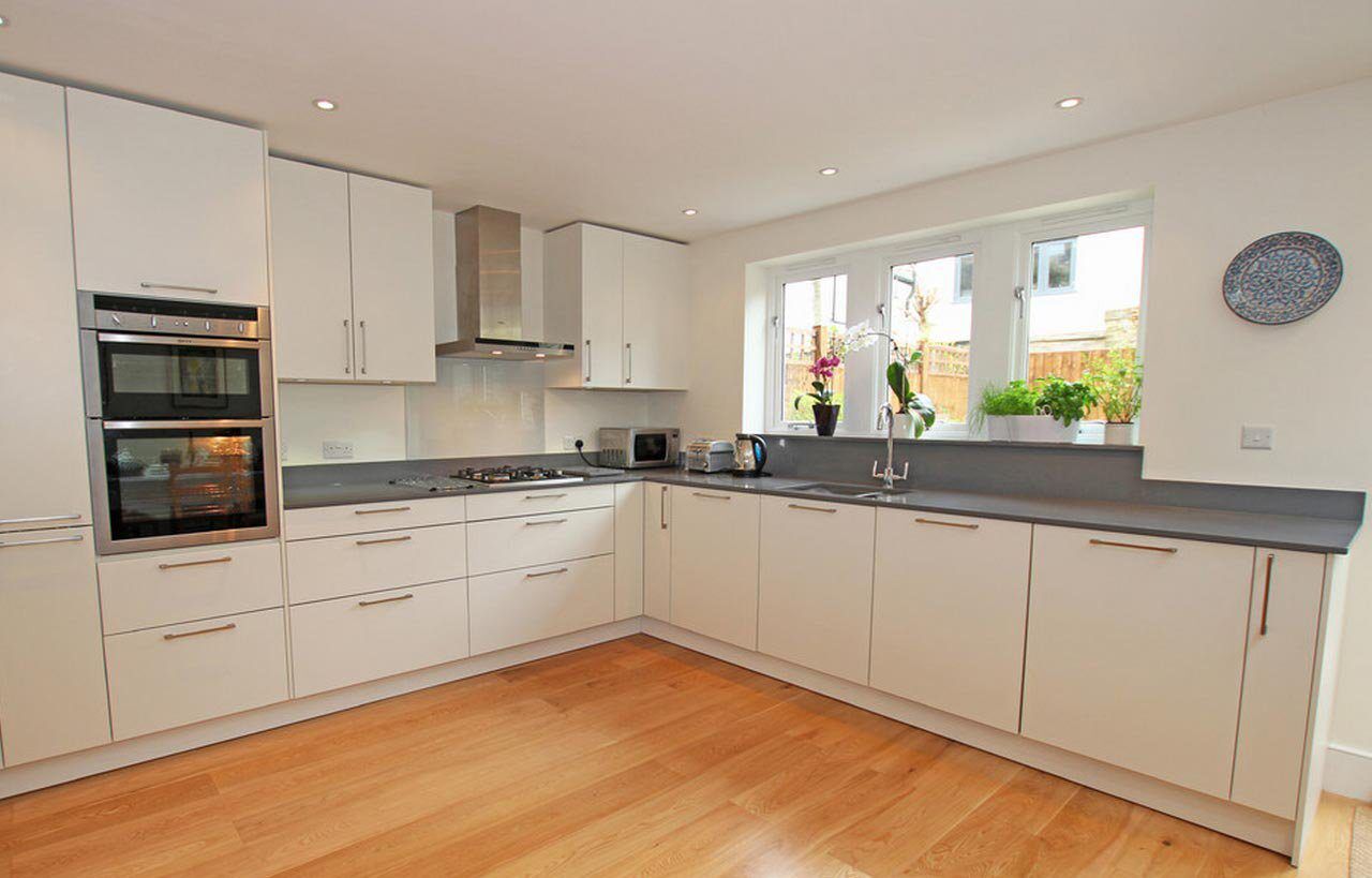 Slate Grey Quartz worktops fitted to an L-shaped kitchen with dark grey surfaces and white cabinetry