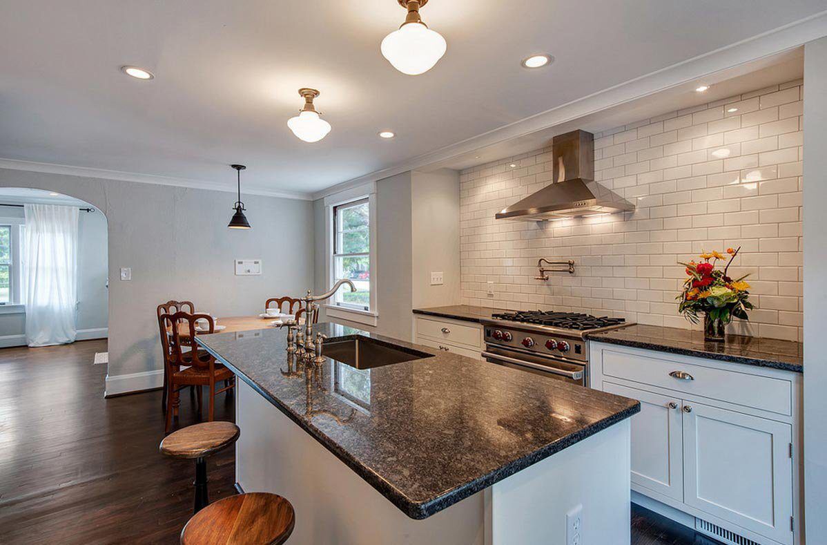 Wide view of a modern kitchen with Steel Grey Granite worktops on the island and perimeter run, showing bar seating and pendant lighting above the island.