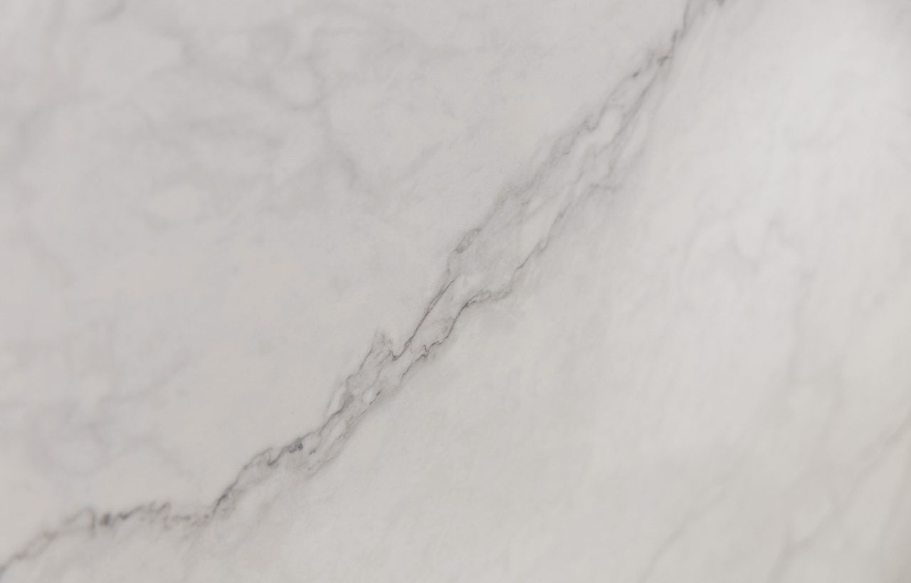 Statuario Venato Porcelain slab detail with a stronger grey diagonal vein and fine branching lines on a pale background.