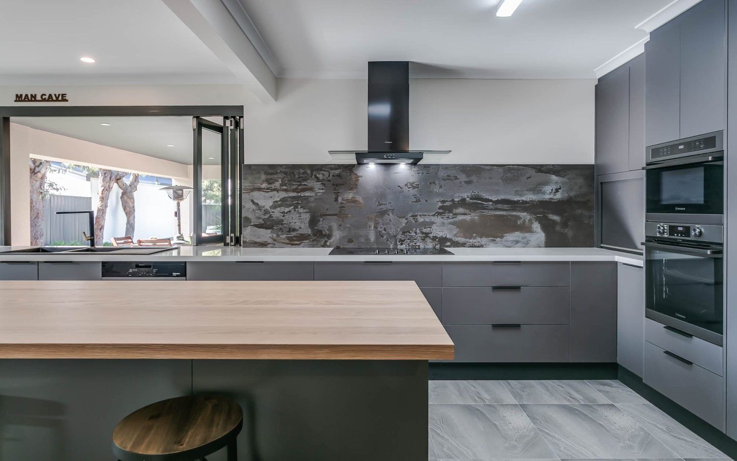 Trilium Porcelain worktop and full-height splashback installed in a modern kitchen with grey units and a timber breakfast bar.