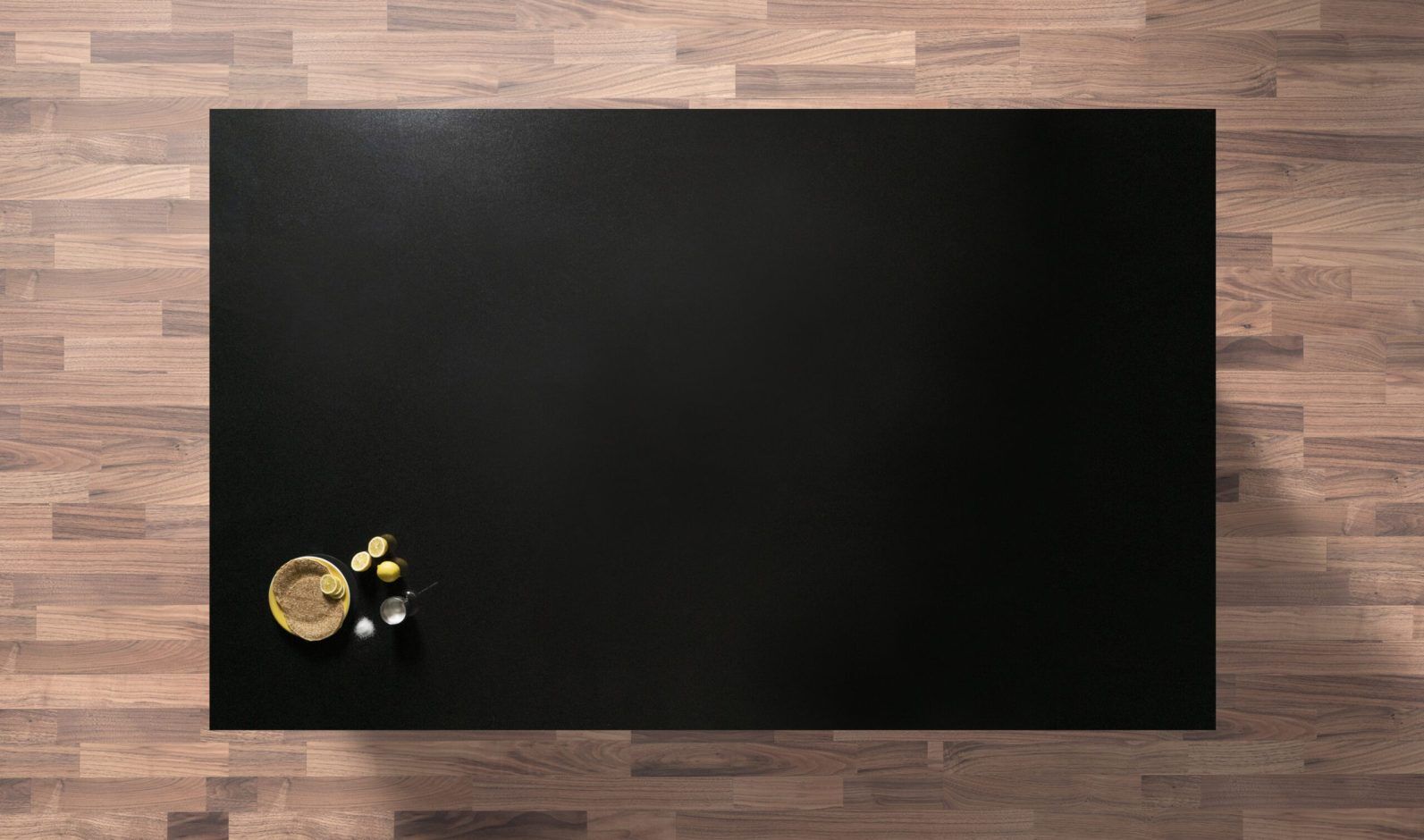 Overhead view of an Absolute Black Granite island worktop with a polished finish, photographed from above with a small coffee cup and spoon in the corner.
