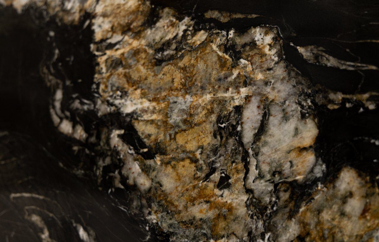 Close up slab photo of African Fusion Granite showing bold gold and amber mineral movement with black and white contrast through the stone.