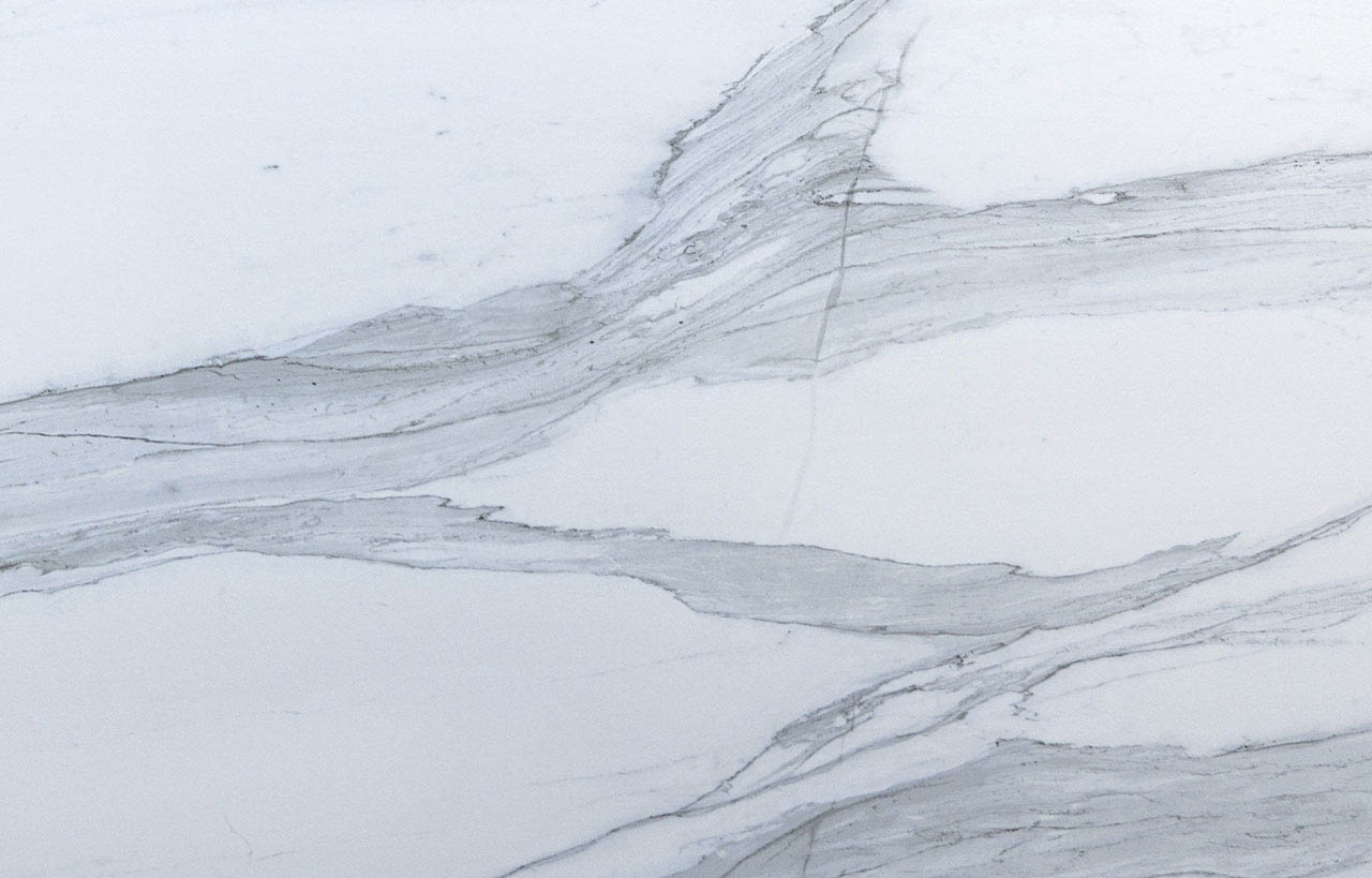 Close up of Bianco Lasa Porcelain slab showing layered grey veining across a white background