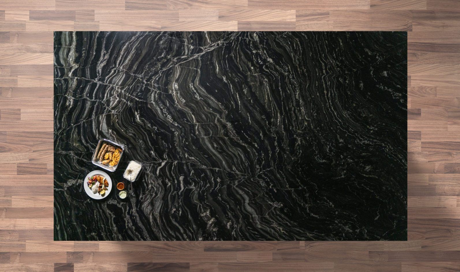 Overhead view of a Black Storm Granite island worktop showing bold natural veining, photographed from above with a small styled tray in the corner.