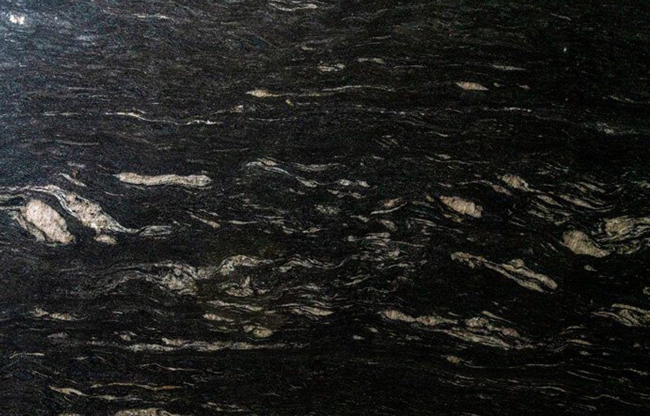 Close up slab photo of Cosmic Black Granite showing sweeping veining and layered mineral patterning through the dark surface.