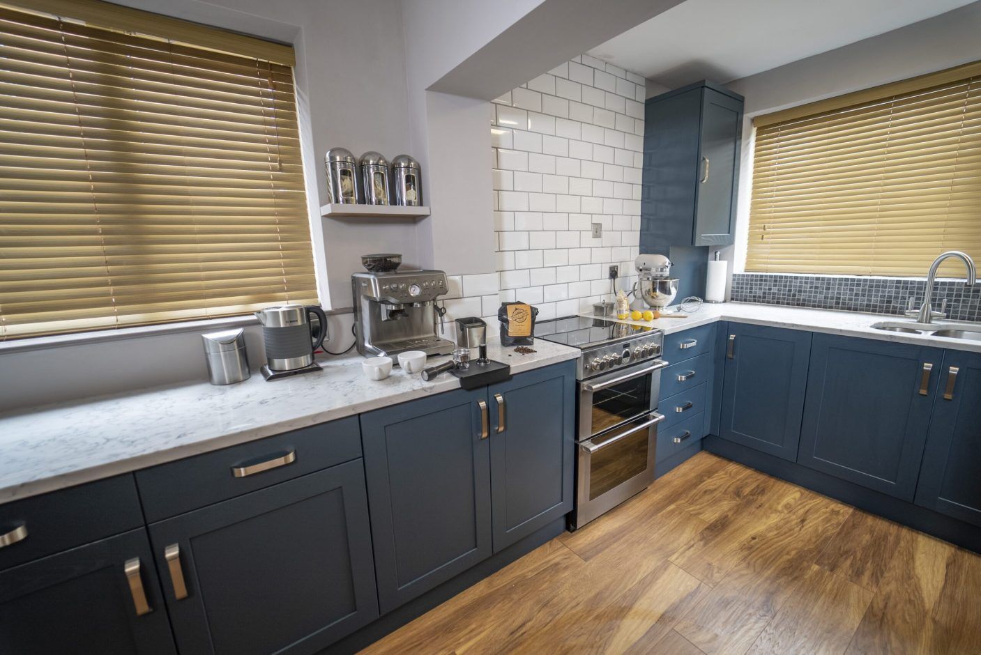 Arabescato Quartz worktops throughout a kitchen with dark blue cabinetry, showing grey veining across the bright surface