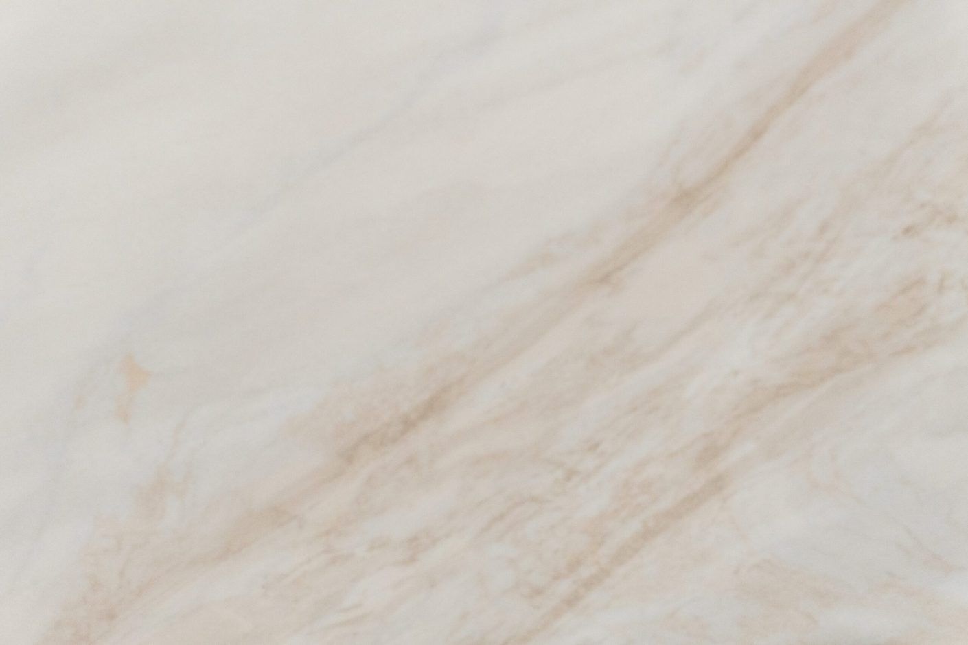 Fusion Gold Porcelain close-up showing soft beige and gold veining drifting across a pale surface