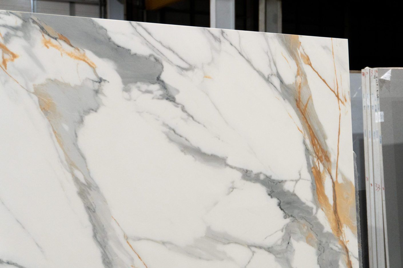 Calacatta Gold Borgnini Porcelain close-up showing a bright white base with bold grey veining and warm gold accents