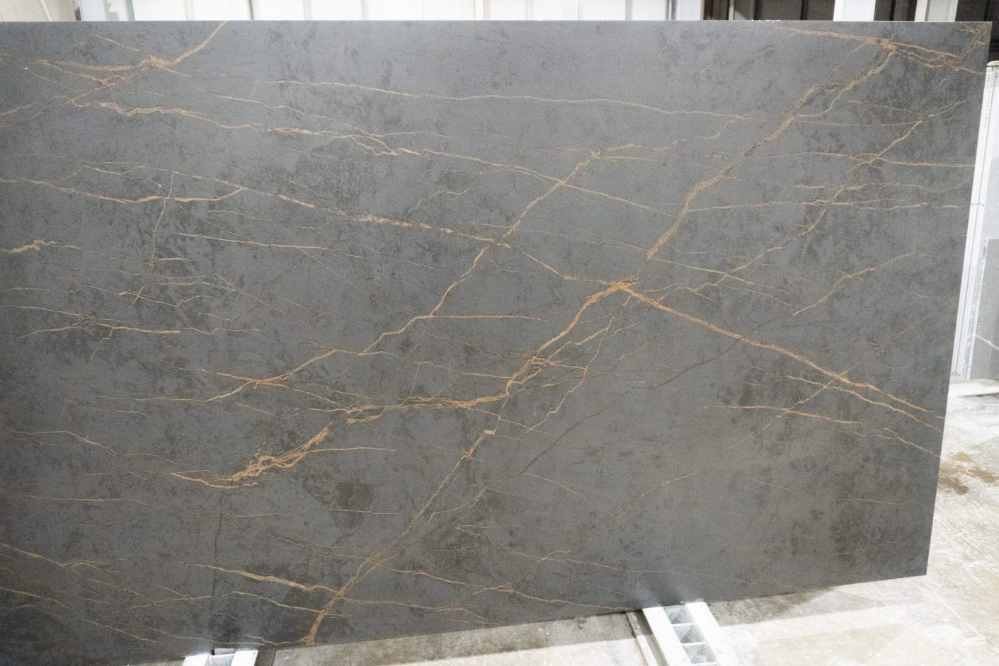 Gold Laurent Porcelain slab in a warehouse setting with long gold veining lines across dark grey surface