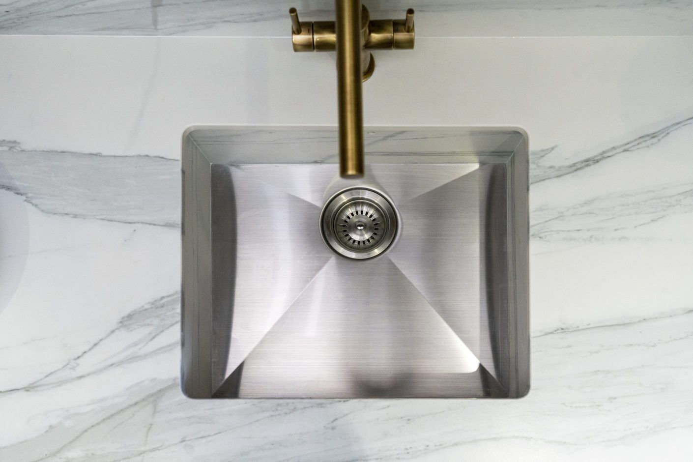 Bianco Lasa Porcelain worktop with undermount stainless steel sink and brushed brass tap above