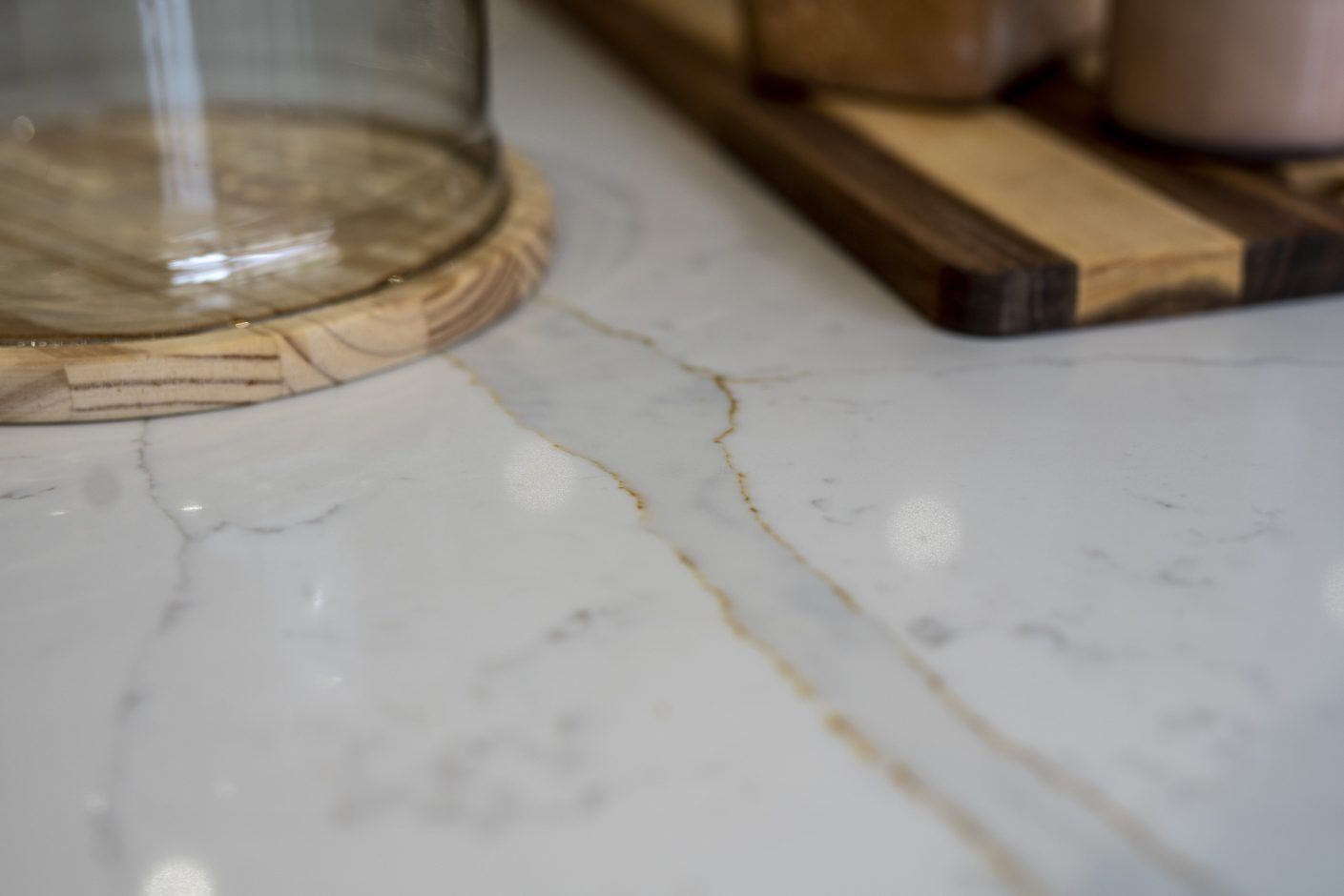 Close up of Gold Calacatta worktop surface showing warm veining beneath glassware