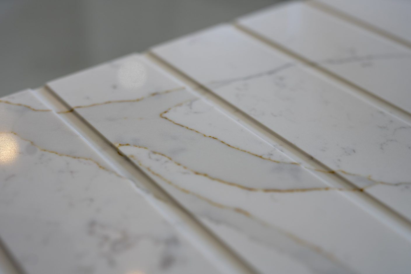 Gold Calacatta worktop with warm veining and precision cut drainer grooves