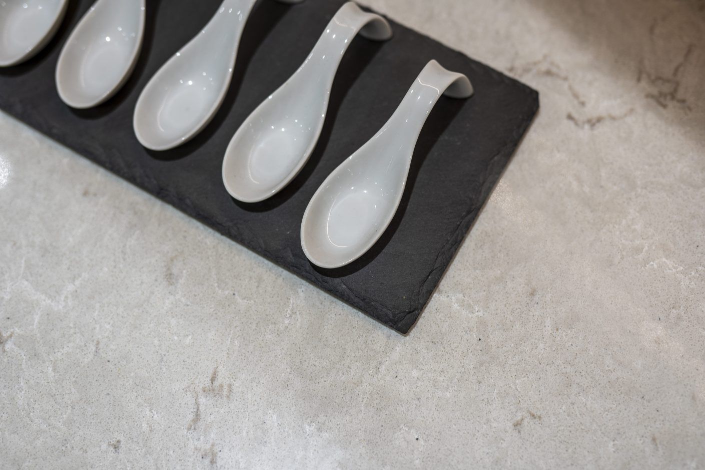 Grey Drift Quartz worktop close-up showing soft stone-effect movement with kitchen spoons on the surface