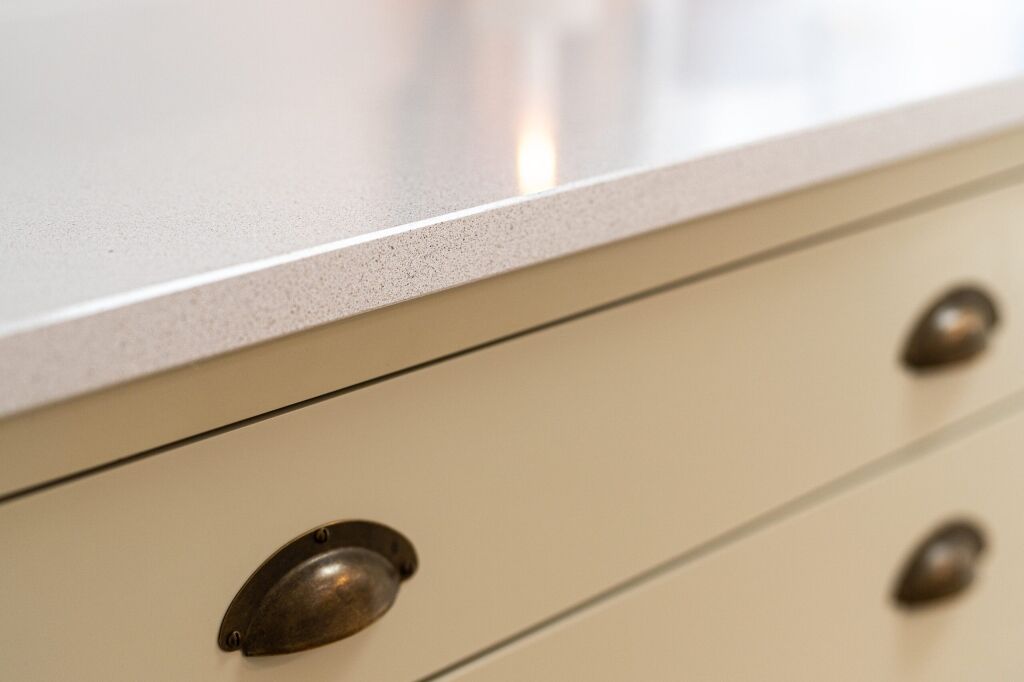 Ice White Quartz worktop edge close-up above cream kitchen drawers showing a clean, straight profile