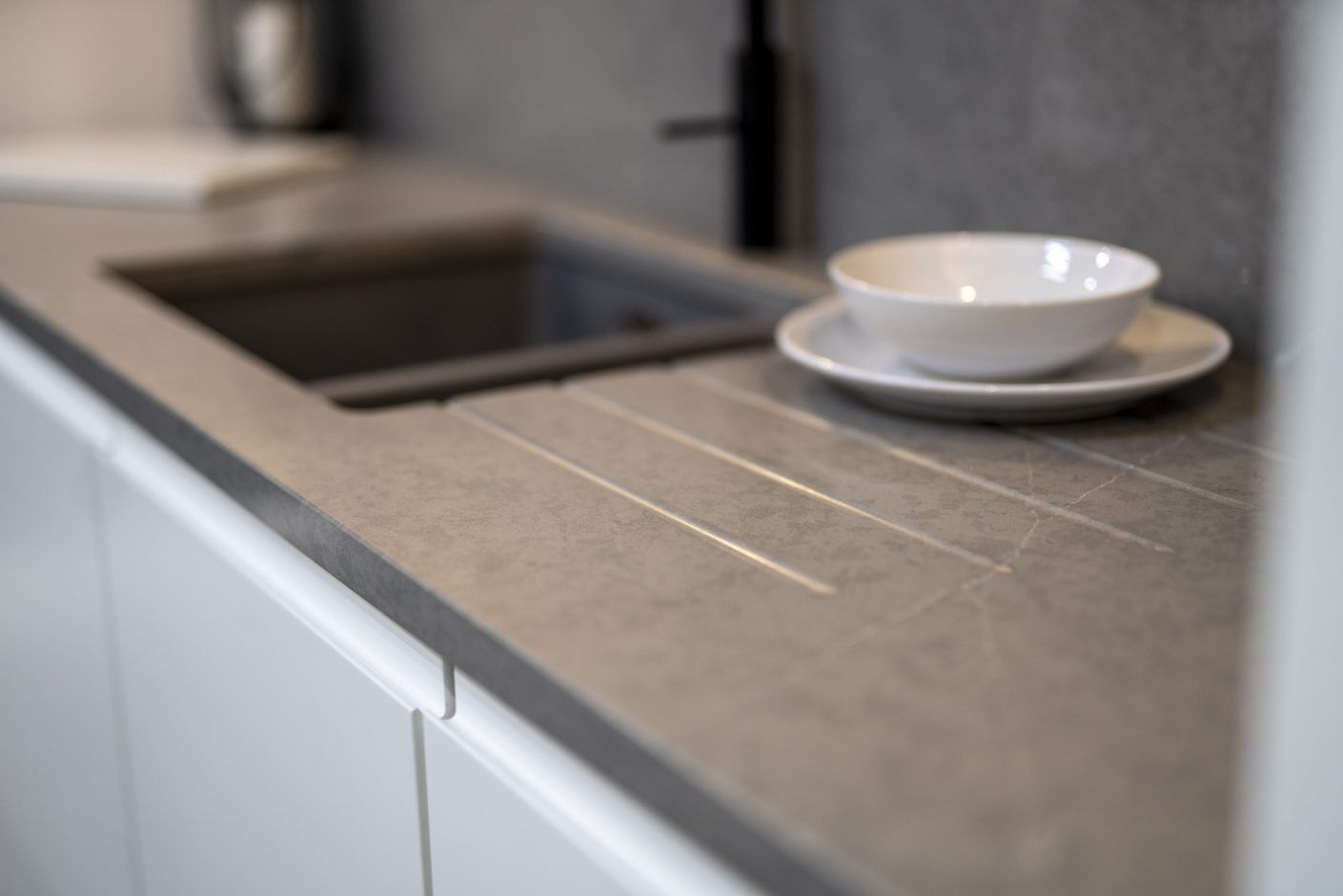 Pietra Grey Quartz drainer grooves beside a sink showing dark grey stone-effect surface with fine linear detail