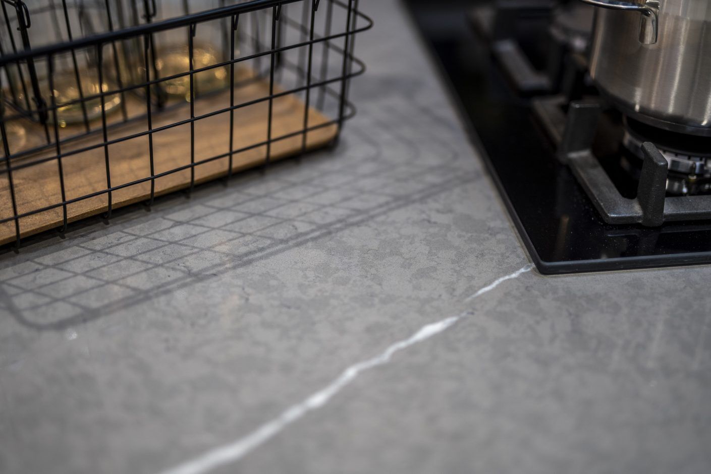 Pietra Grey Quartz close-up showing a crisp white vein running through a dark grey stone-effect surface near a hob