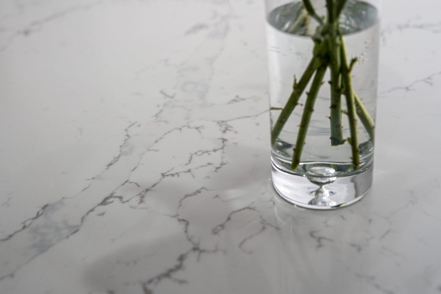 Close up of White Calacatta Quartz worktop surface with grey veining and vase of flowers