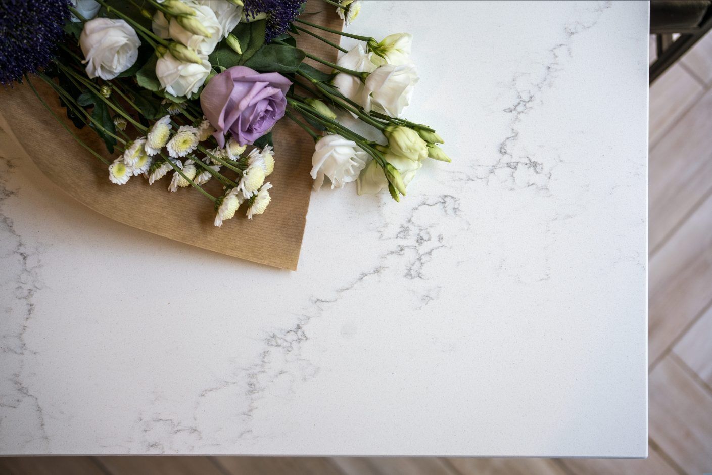 Olympus White Quartz worktop close-up with subtle grey veining beside flowers and kitchen styling