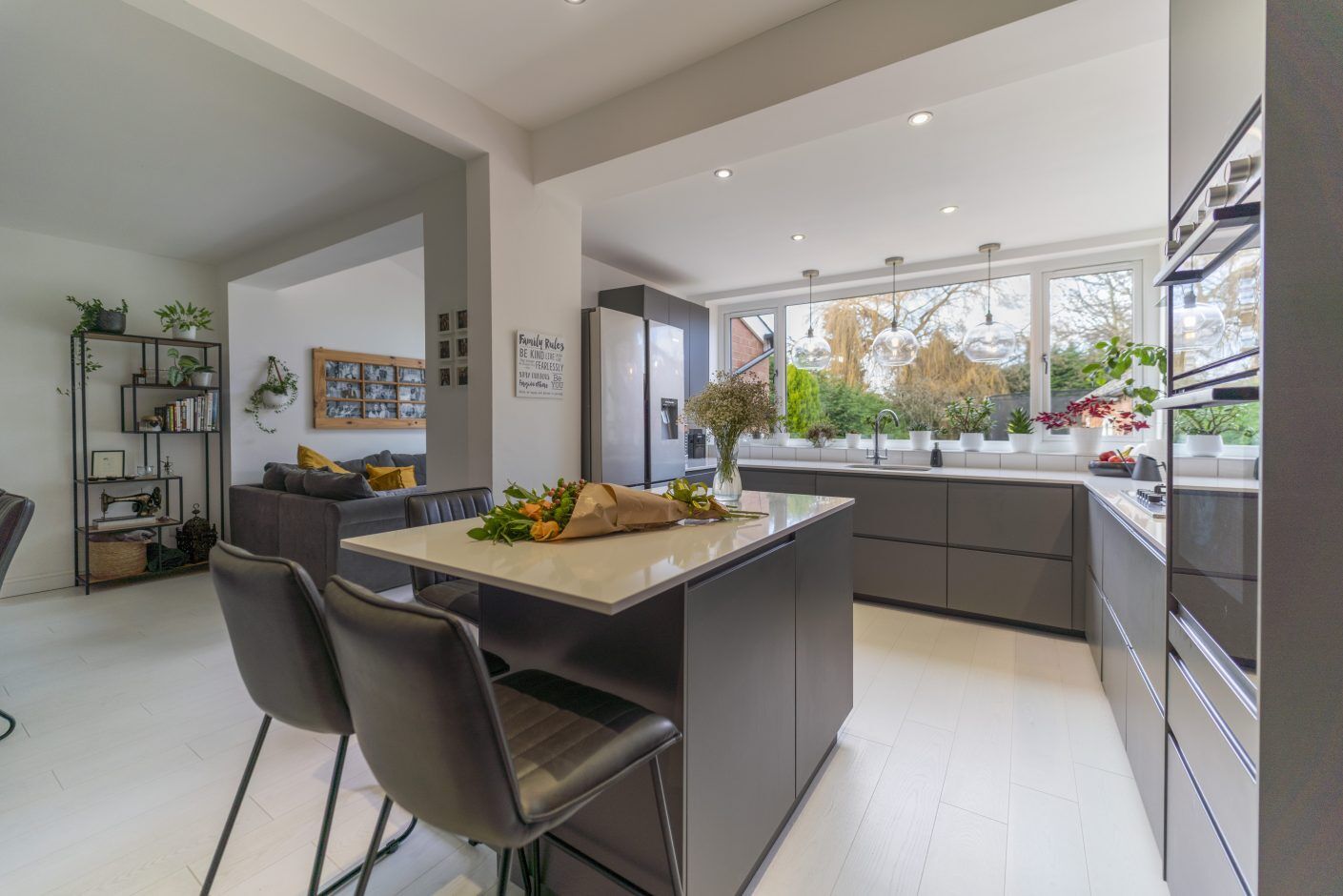 Open-plan kitchen with Blanco Zeus Quartz island worktop and bright white surface with seating in front of large windows